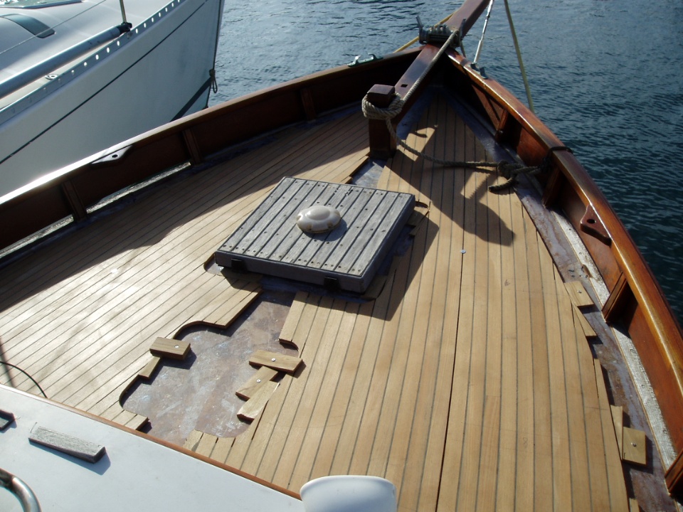 Pont d'un bateau en bois avec une surface en teck et un panneau de regards au centre.