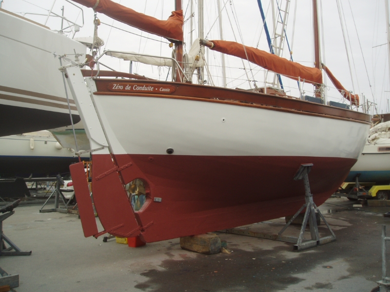 Bateau de plaisance portant le nom 'Zéro de Conduite', avec une coque blanche et rouge, en cale sèche.