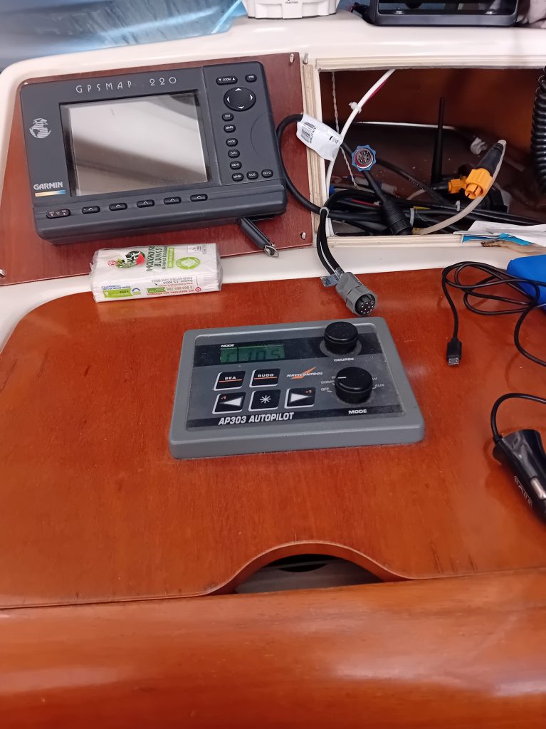 Tableau de bord d'un bateau avec un écran GPS Garmin et un panneau de commande d'autopilote AP303.