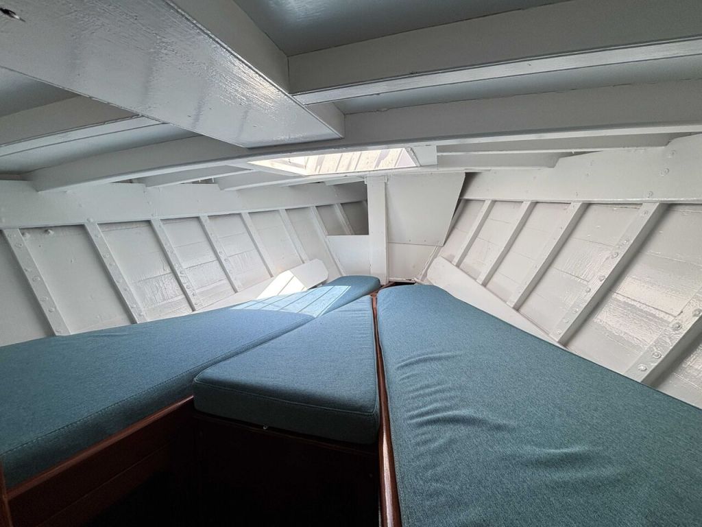 Intérieur d'un bateau avec des banquettes bleues et des murs blancs.