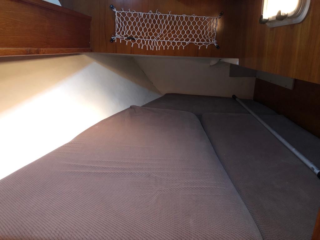 Intérieur d'une cabine de bateau avec un lit double et des murs en bois.