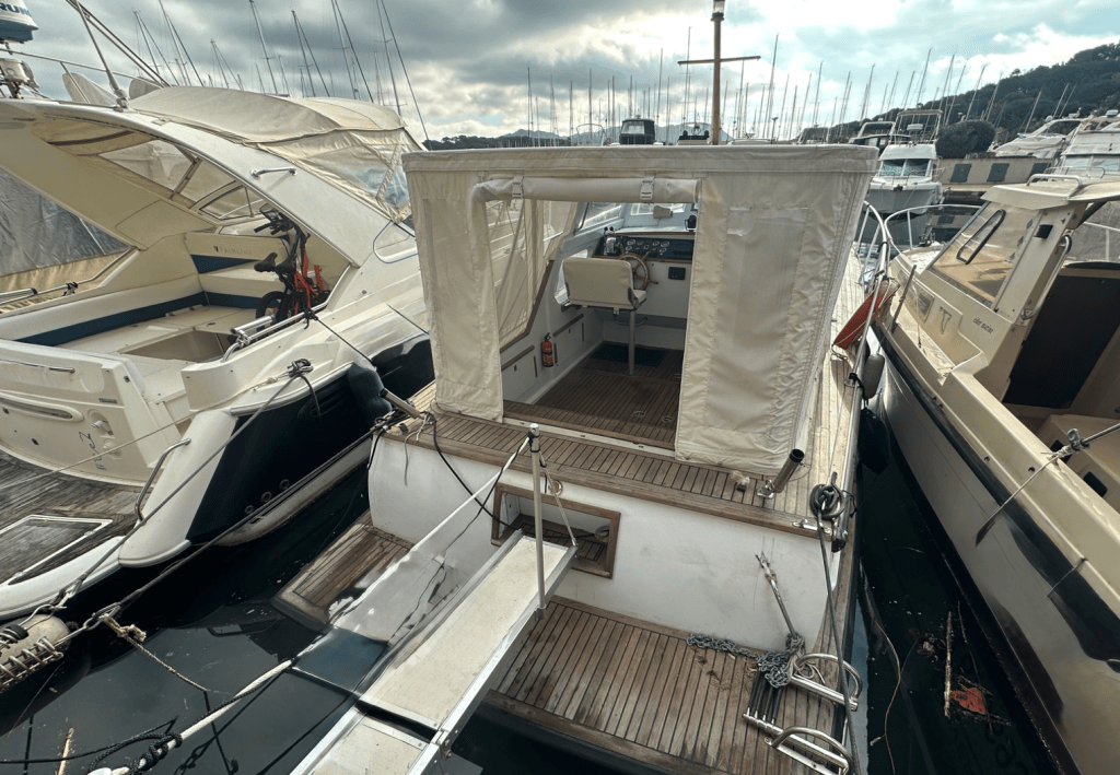 Un bateau amarré dans un port, avec un intérieur visible et un panneau en toile.