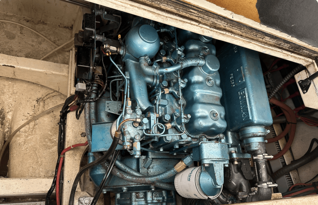 Moteur marin bleu visible à l'intérieur d'un bateau, avec divers composants et tuyaux connectés.